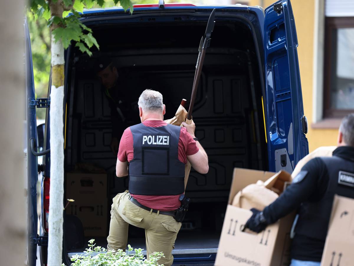 Polizisten tragen Gegenstände, darunter mehrere Stichwaffen und Speere, aus dem Wohnhaus des Verdächtigen.