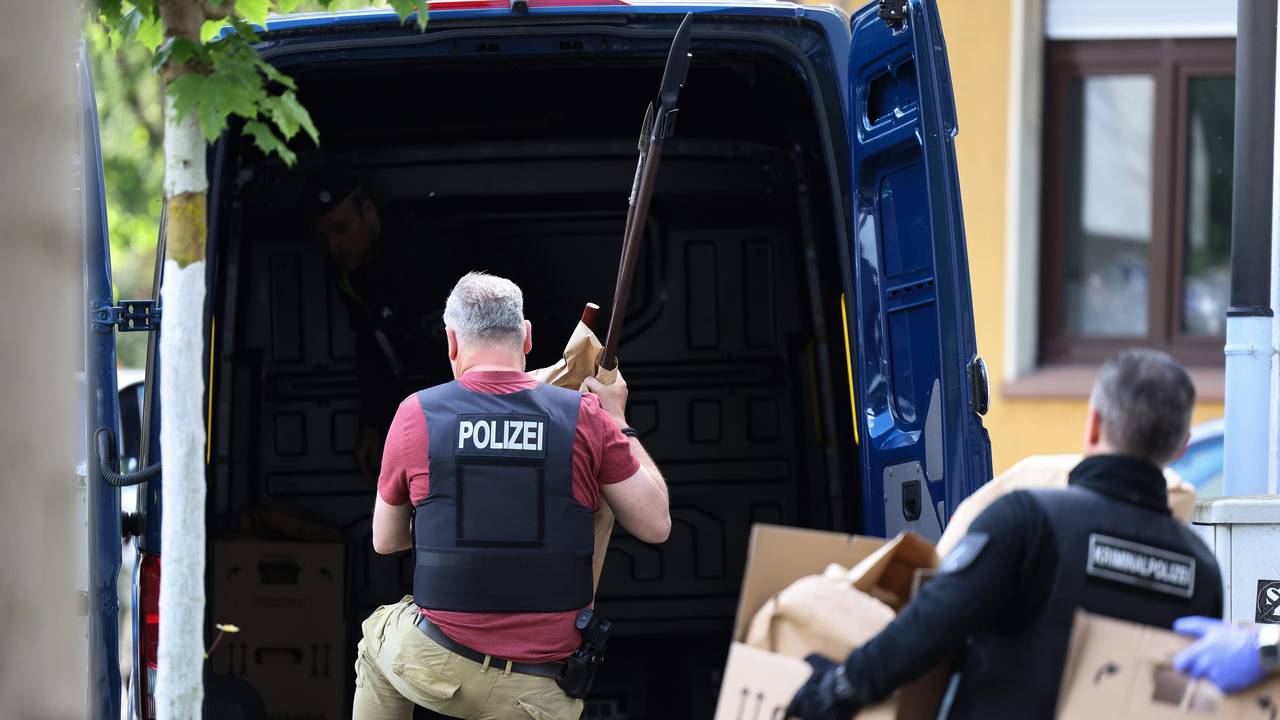 Polizisten tragen Gegenstände, darunter mehrere Stichwaffen und Speere, aus dem Wohnhaus des Verdächtigen.