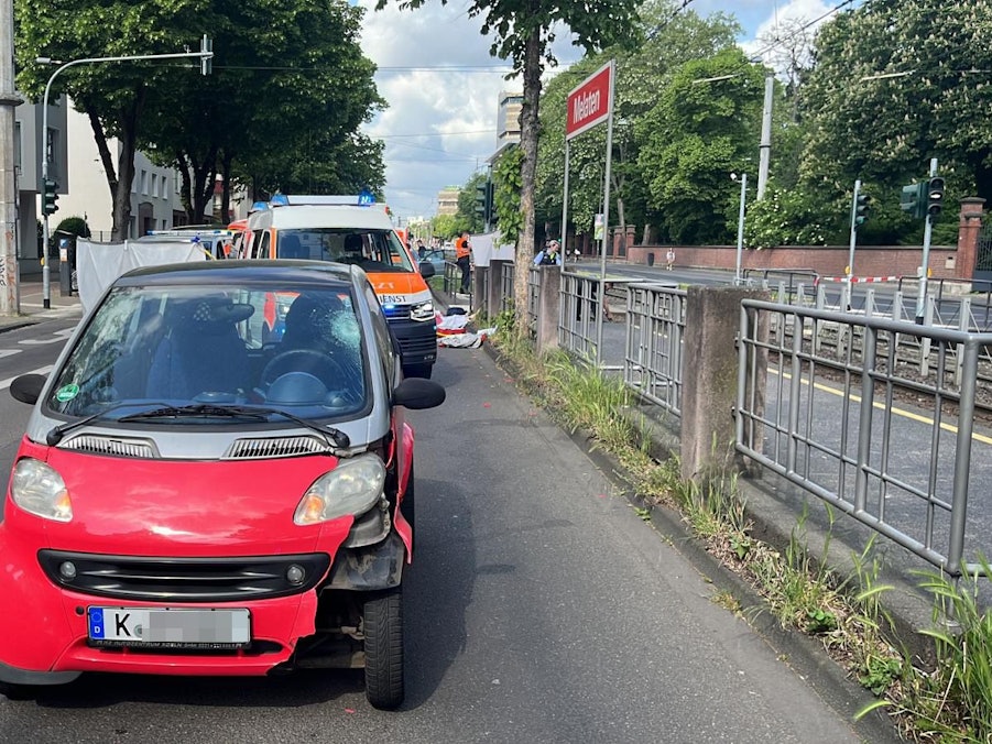 Ein Smart steht mit Beschädigungen auf der Straße, dahinter ein Rettungsfahrzeug.
