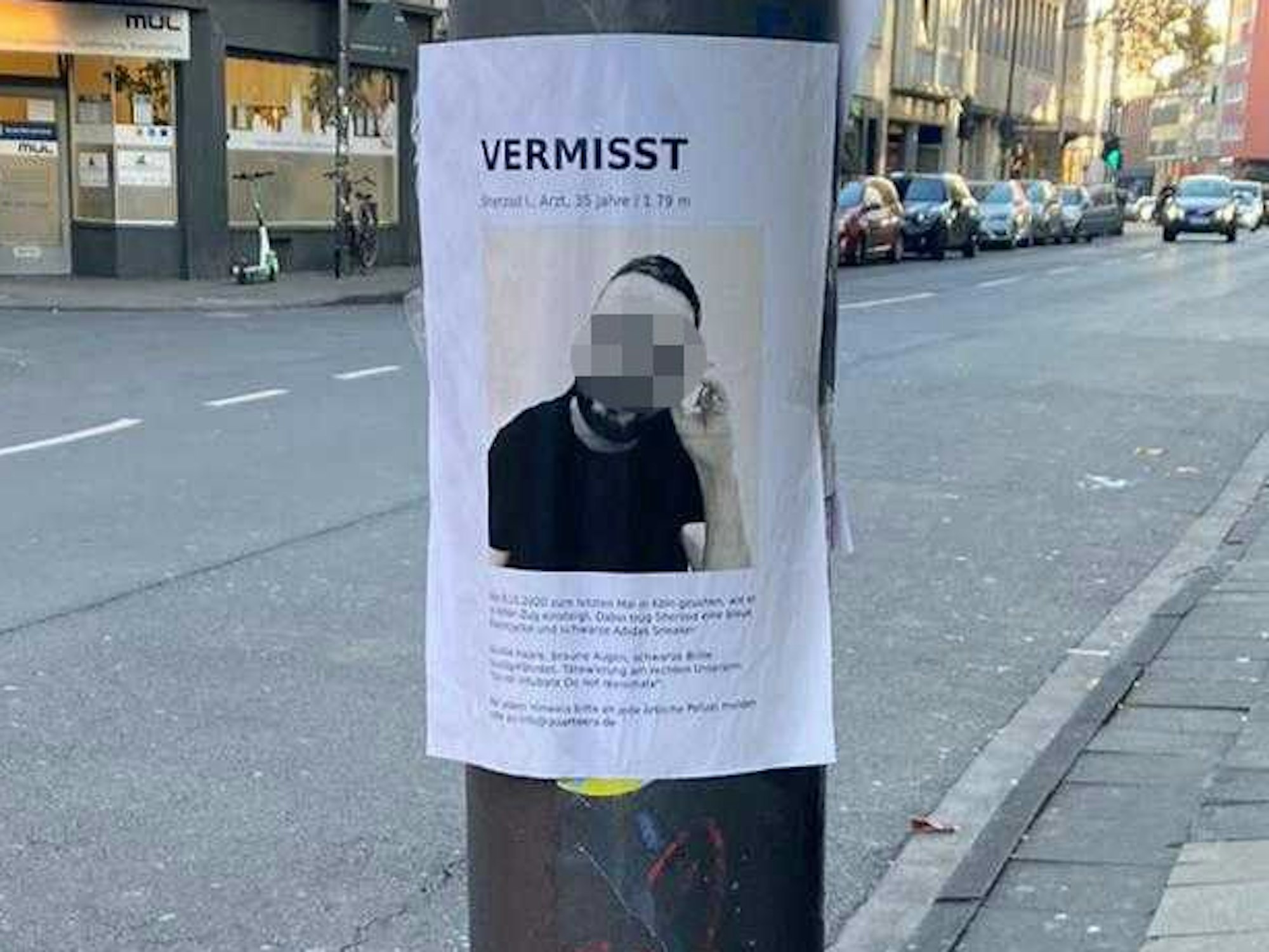 An einem Masten an einer Straße hängt ein Zettel mit dem Foto eines Mannes, darüber steht „Vermisst“.