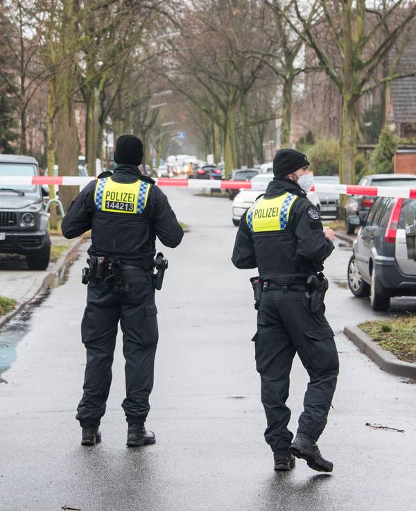 Polizisten sperren eine Straße in einem Wohngebiet.
