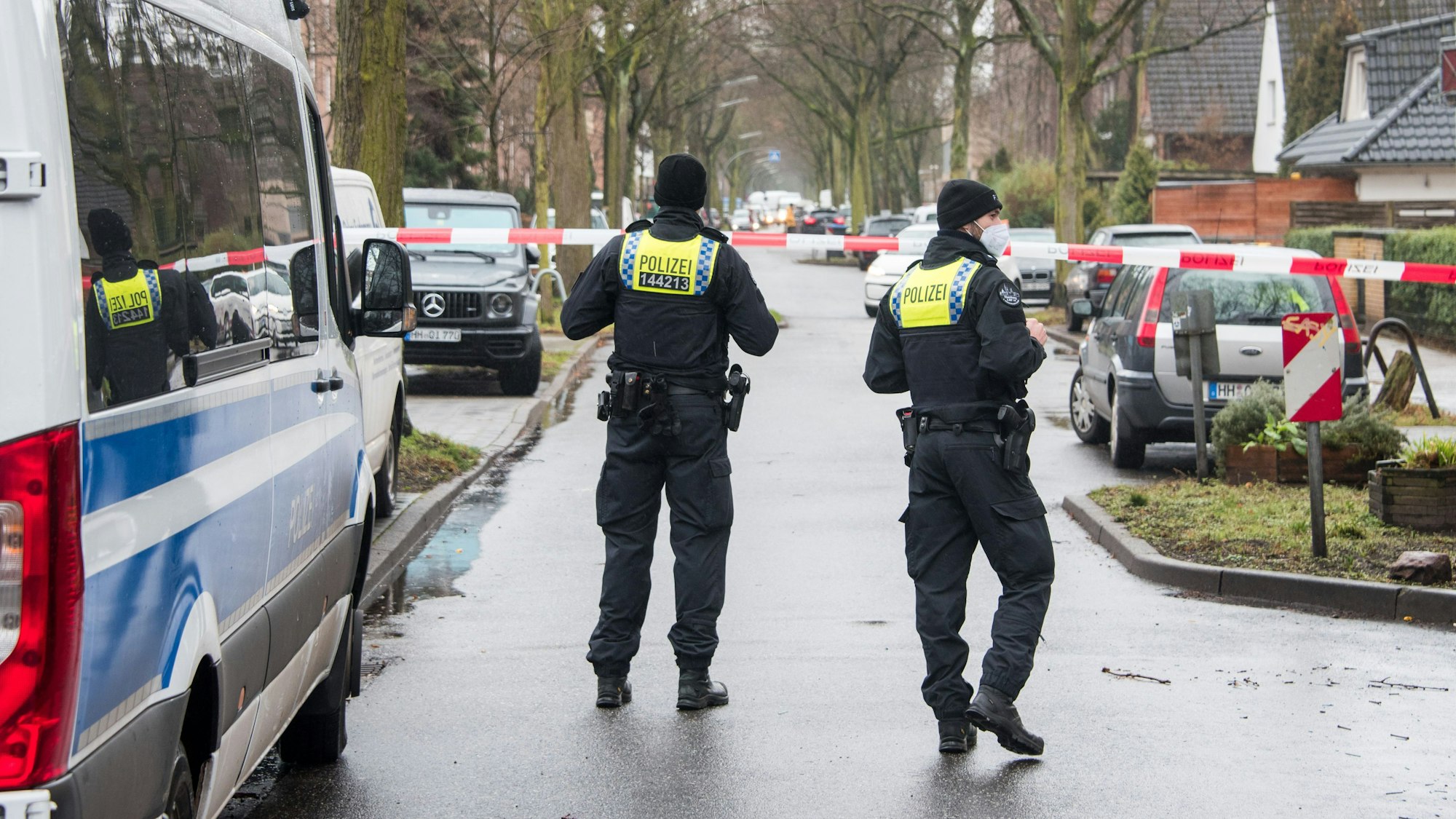 Polizisten sperren eine Straße in einem Wohngebiet.