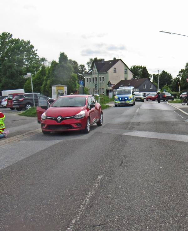 Ein roter Renault Clio steht nach einem Unfall auf der Straße – dahinter ein Polizeifahrzeug.