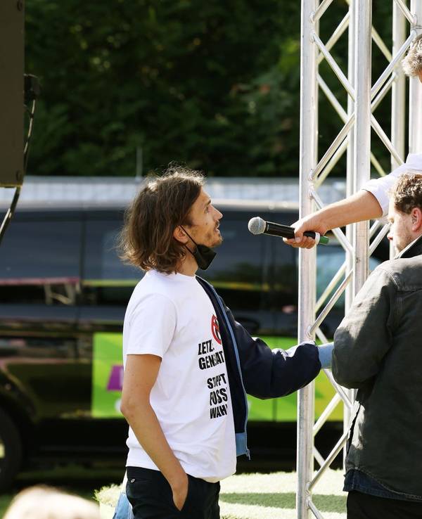 Robert Habeck (r, Bündnis 90/Die Grünen), Bundesminister für Wirtschaft und Klimaschutz, redet mit einen Demonstranten (l), der sich an die Bühne geklebt hat.