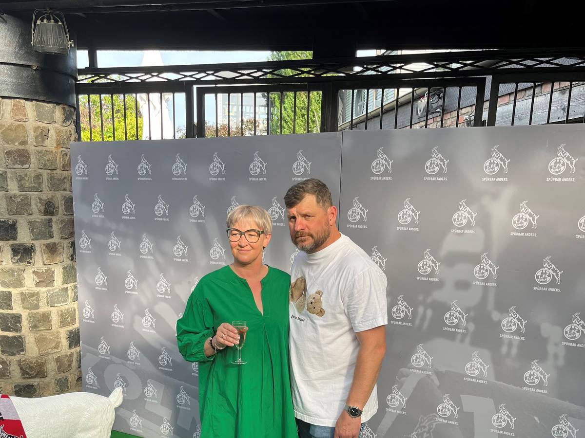 Steffen Baumgart und seine Frau Katja werden vor einem FC-Hintergrund beim Saison-Ausklang abgelichtet.