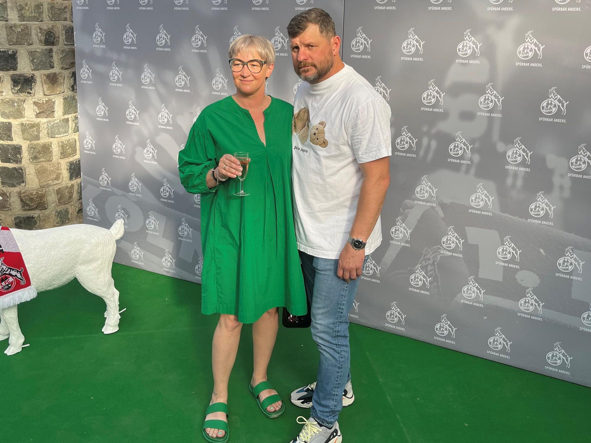 Steffen Baumgart und seine Frau Katja werden vor einem FC-Hintergrund beim Saison-Ausklang abgelichtet.