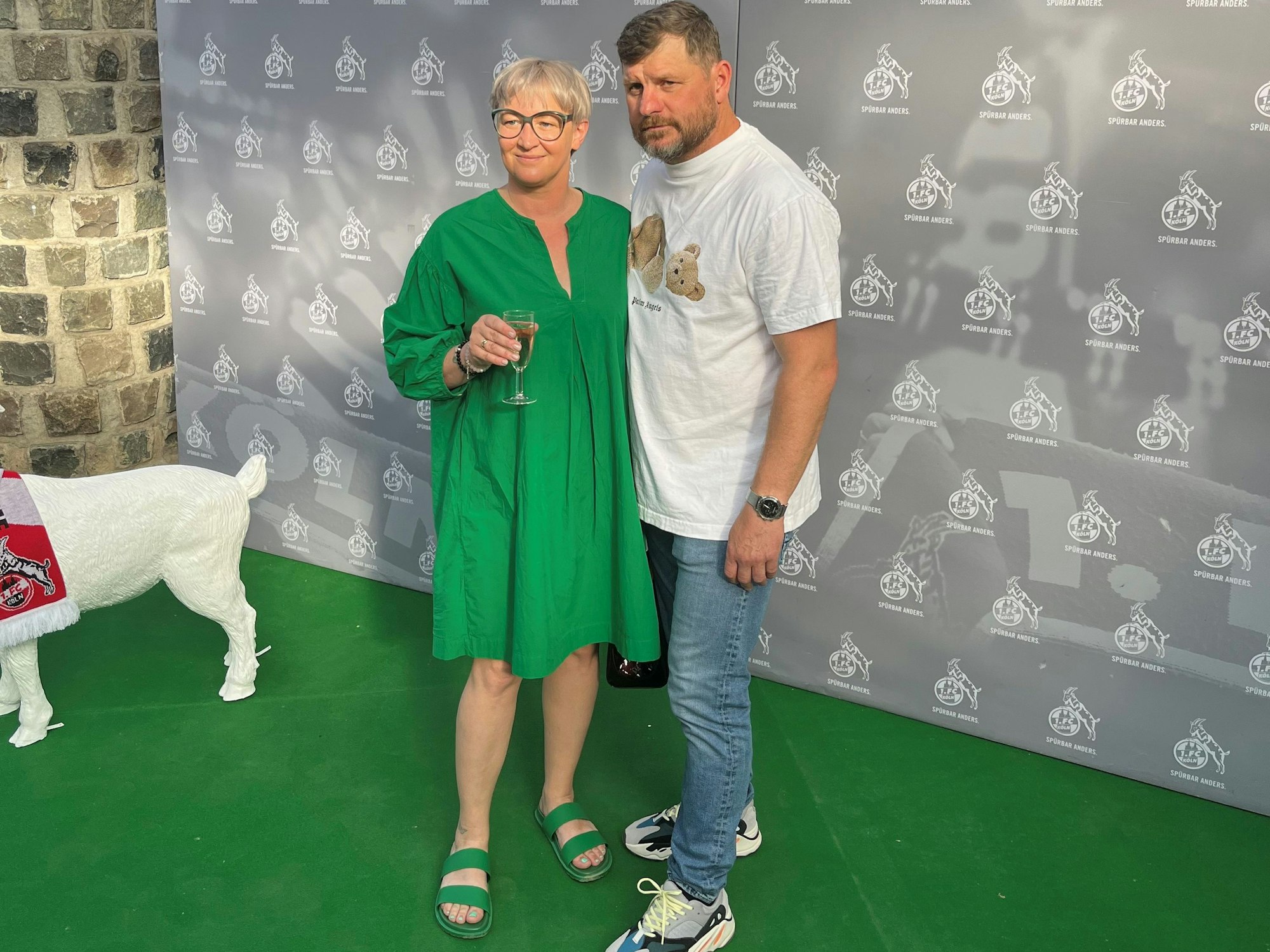 Steffen Baumgart und seine Frau Katja werden vor einem FC-Hintergrund beim Saison-Ausklang abgelichtet.
