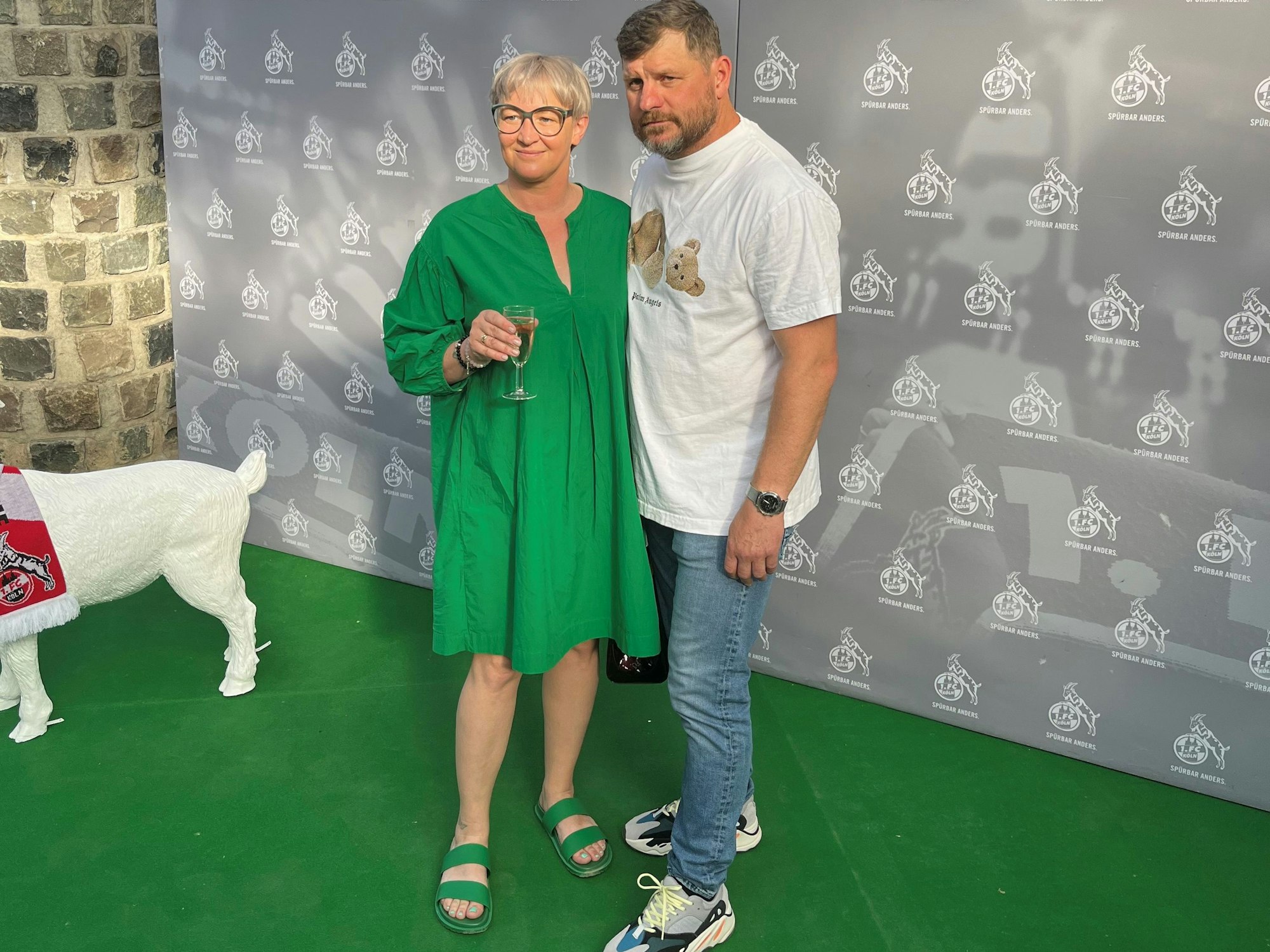 Steffen Baumgart und seine Frau Katja werden vor einem FC-Hintergrund beim Saison-Ausklang abgelichtet.