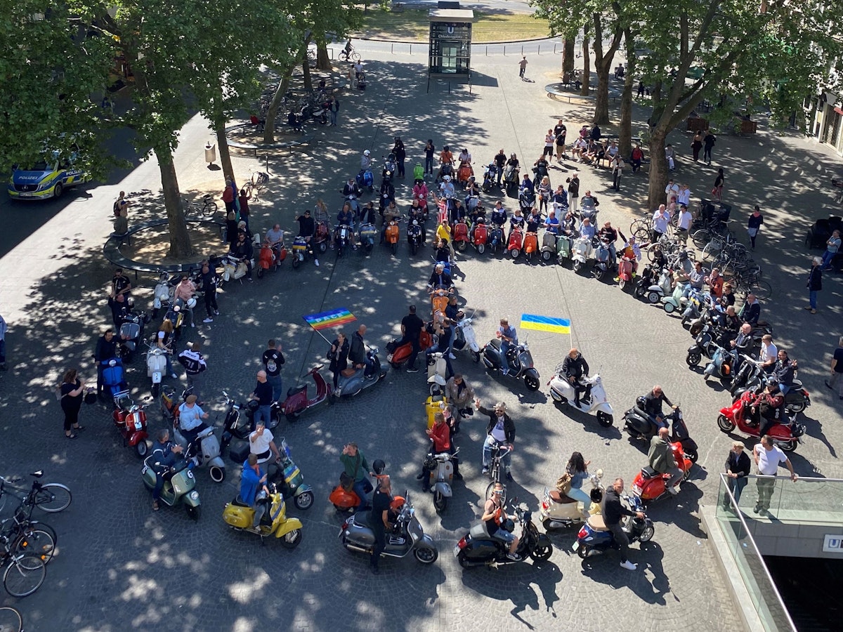 80 Vespas formen auf dem Chlodwigplatz ein Peace-Zeichen.