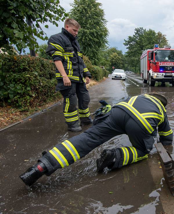 Nach dem Bilderbuchwochenende warnt der Deutsche Wetterdienst vor einem Wetter-Umschwung. Starkregen und Überflutungen sind möglich. Dasundatierte Symbolbild aus NRW zeigt Feuerwehrleute nach Starkregen an einer überfluteten Straße.