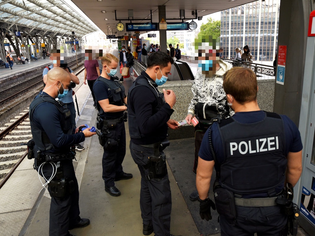 Beamte der Polizei kontrollieren eine Person am Kölner Hauptbahnhof.