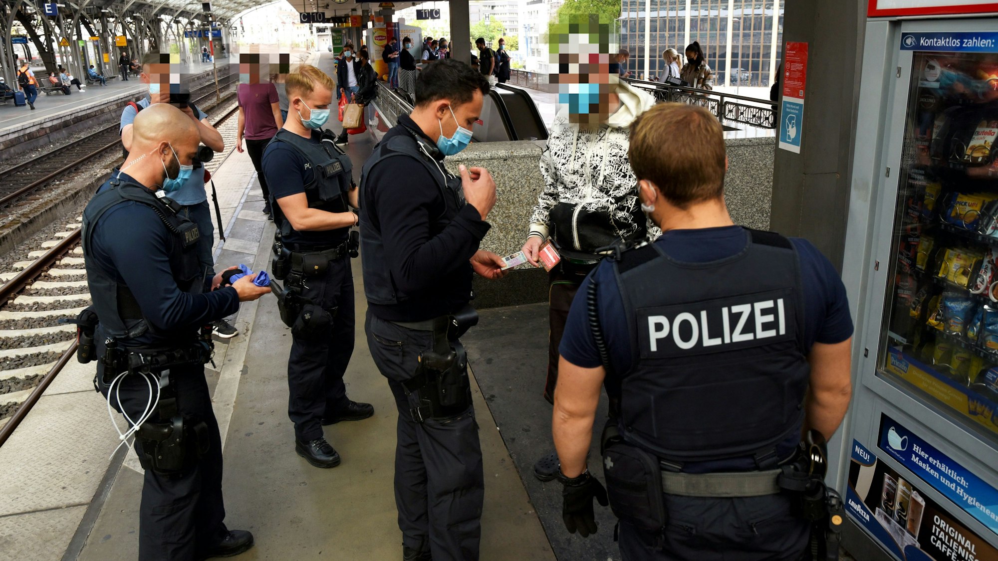 Kräfte von Polizei, Ordnungsamt und DB Sicherheit kontrollieren auf einem Bahnsteig des Kölner Hauptbahnhofs einen Mann.