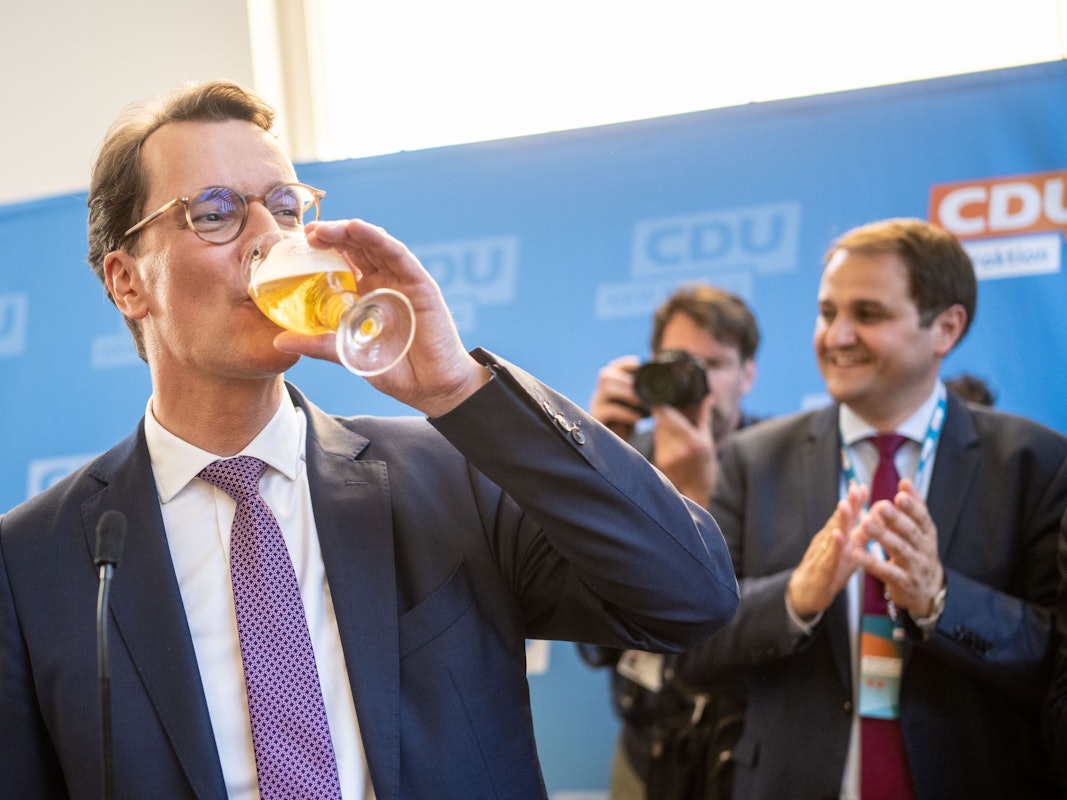 Hendrik Wüst nimmt in Düsseldorf auf seiner Wahlparty ein Schluck von einem Bier.
