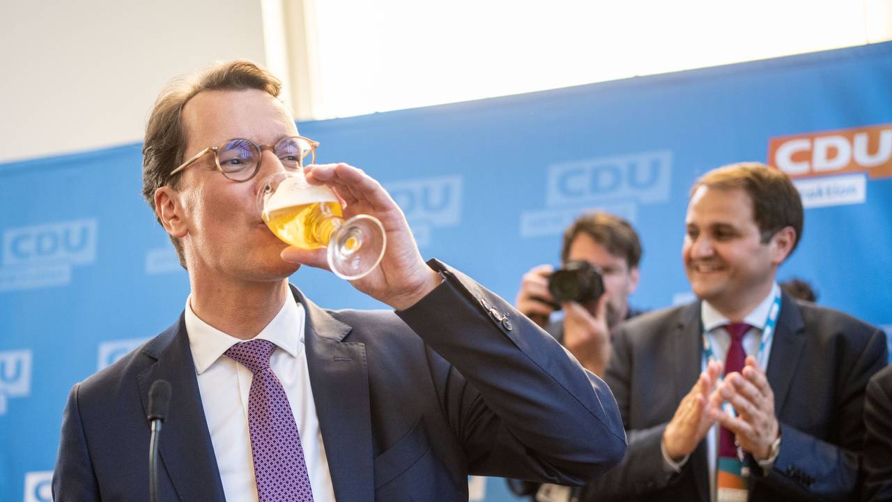 Hendrik Wüst nimmt in Düsseldorf auf seiner Wahlparty ein Schluck von einem Bier.