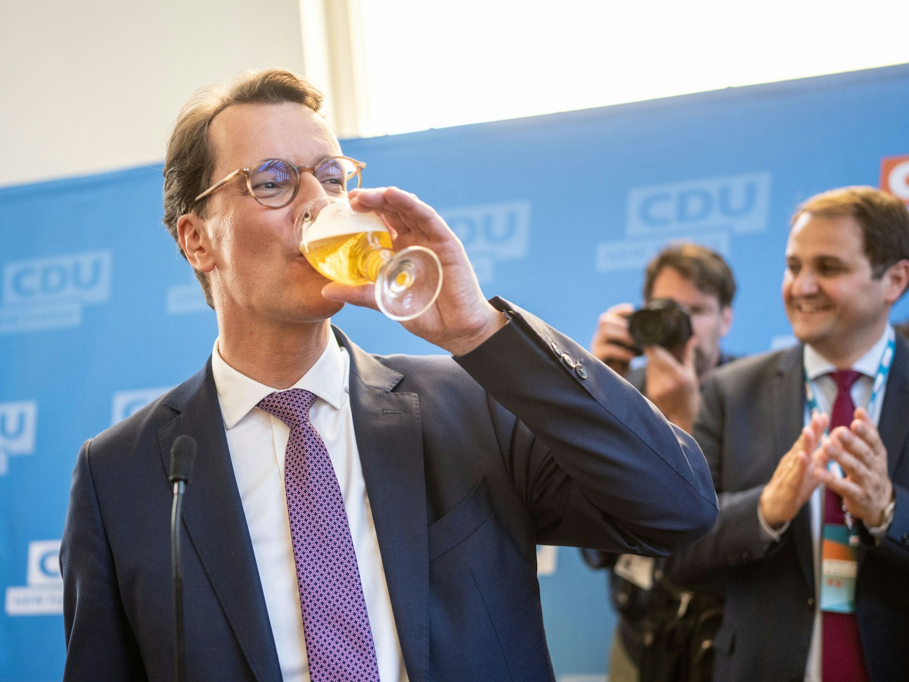 Hendrik Wüst nimmt in Düsseldorf auf seiner Wahlparty ein Schluck von einem Bier.