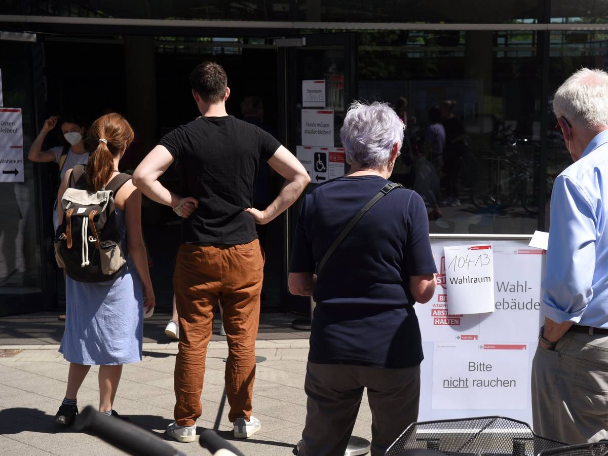 Menschen stehen vor einem Wahllokal in Köln in einer Schlange.