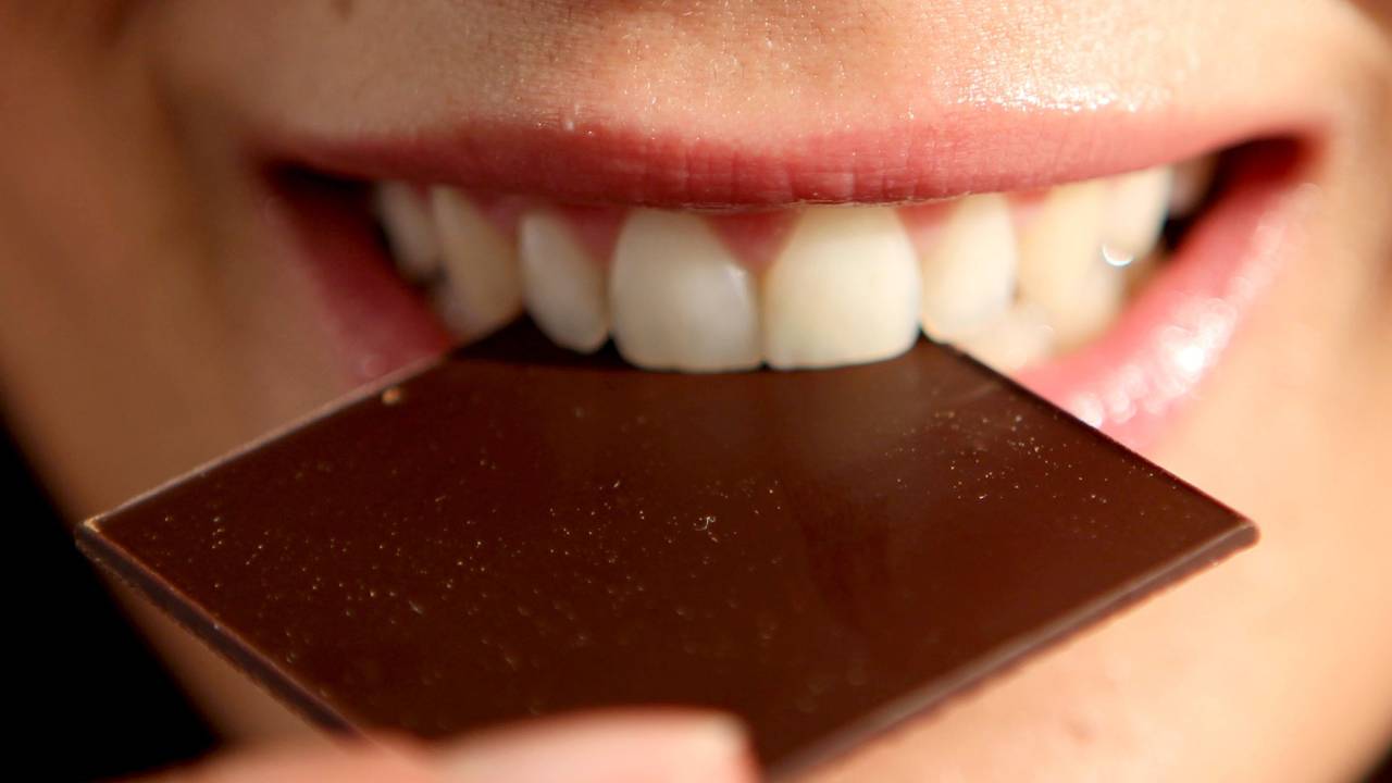 Eine Frau beißt in ein Täfelchen Schokolade. (zu dpa: «Schokofest Weihnachten, Schokoladenland Deutschland») +++ dpa-Bildfunk +++