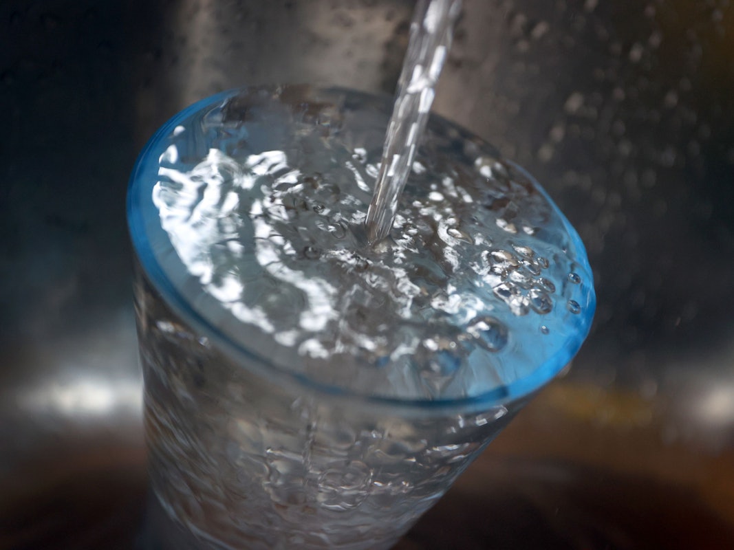 Das Bild aus dem Jahr 2021 zeigt ein Glas, welches im Spülbecken steht und mit Leistungswasser gefüllt wird.