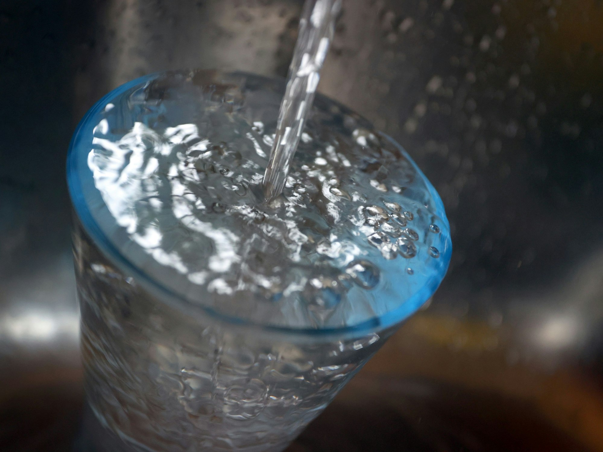 Das Bild aus dem Jahr 2021 zeigt ein Glas, welches im Spülbecken steht und mit Leistungswasser gefüllt wird.