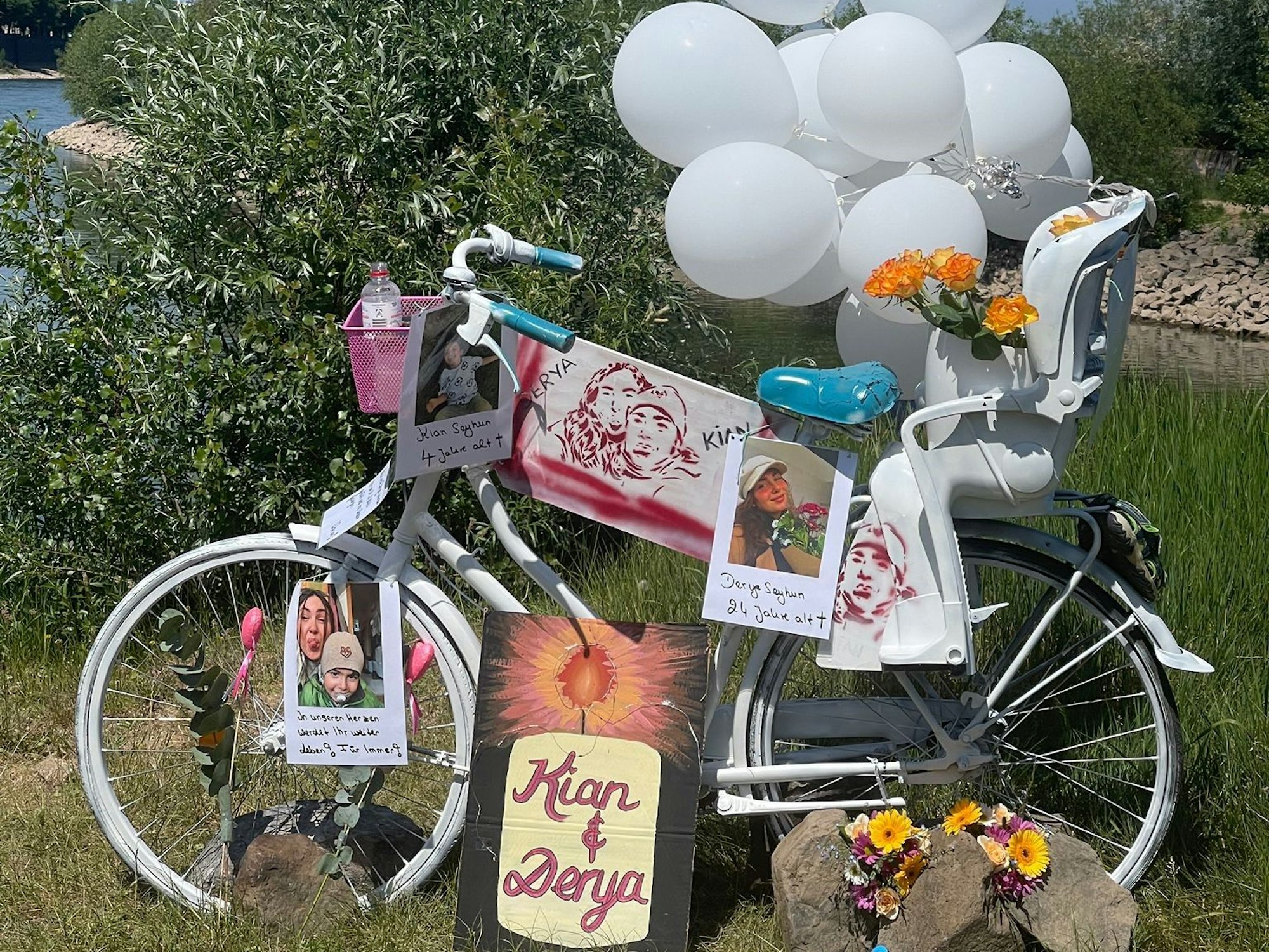An einem Fahrrad samt Kindersitz sind Luftballon, Bilder und Fotos befestigt. Auf einem Schild steht „Kian und Derya“.