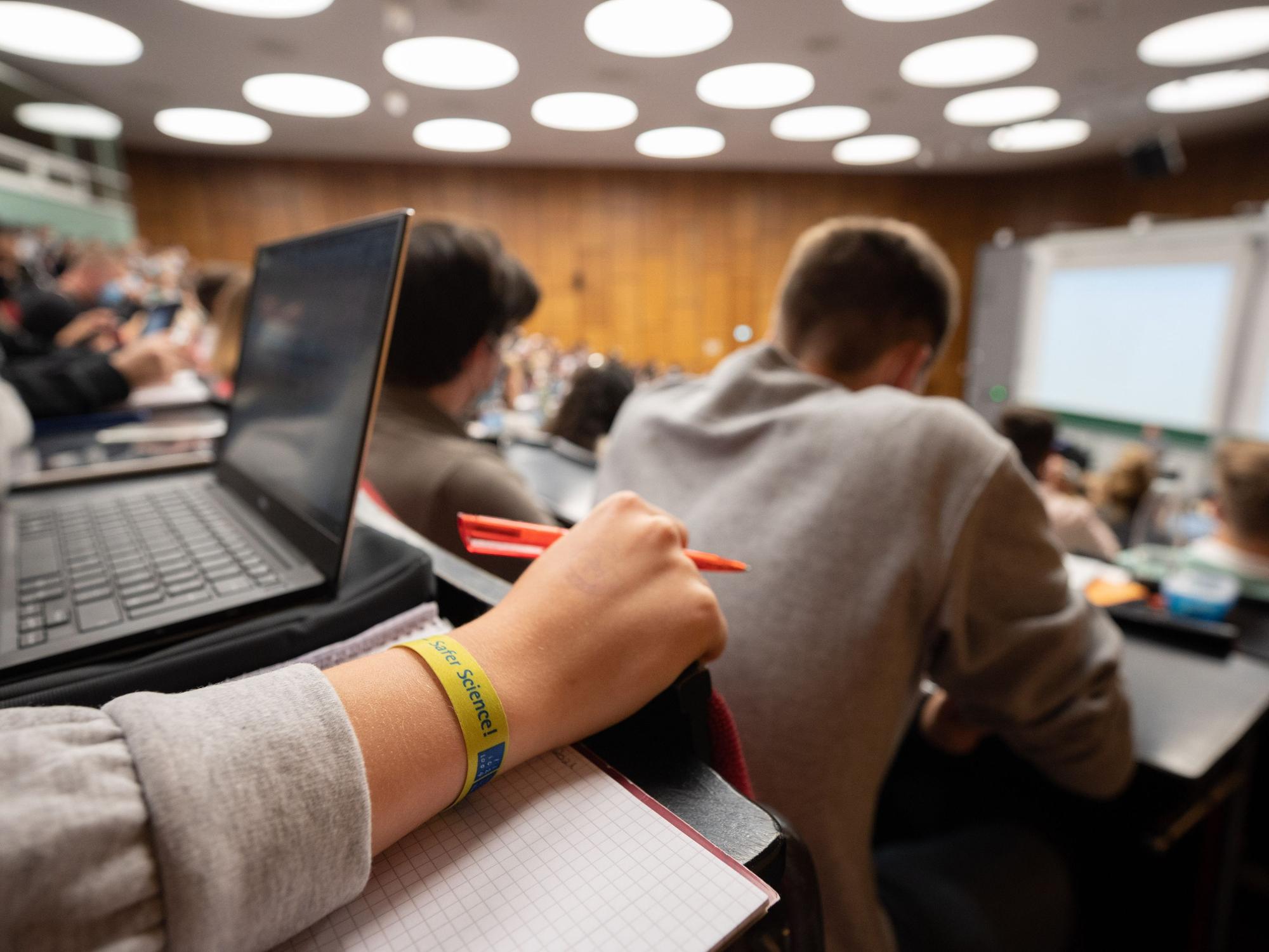 Eine Studentin sitzt mit weiteren Kommilitonen und Kommilitoninnen am 18. Oktober 2021 in einem Hörsaal.