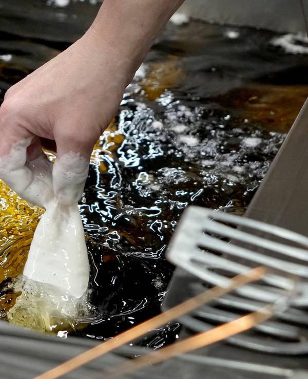 Panierter Fisch wird in heißes Sonnenblumenöl gelegt.