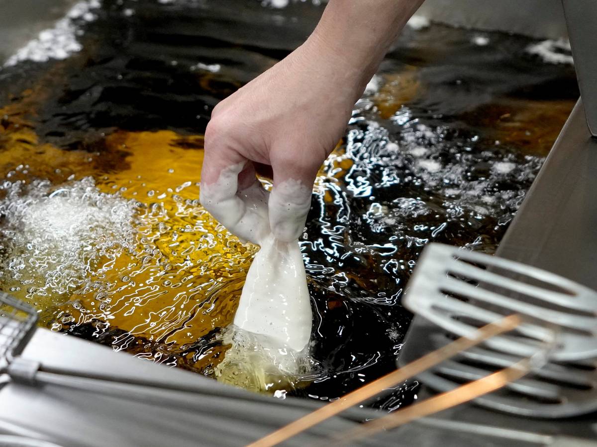 Panierter Fisch wird in heißes Sonnenblumenöl gelegt.