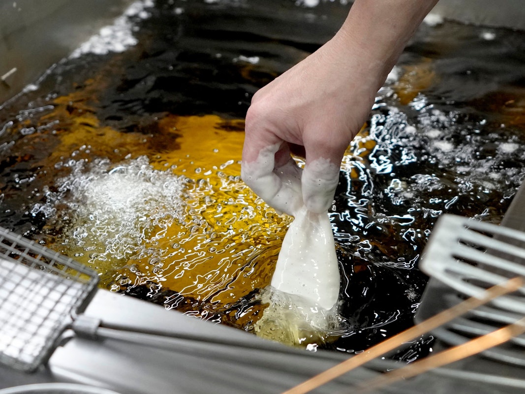 Panierter Fisch wird in heißes Sonnenblumenöl gelegt.