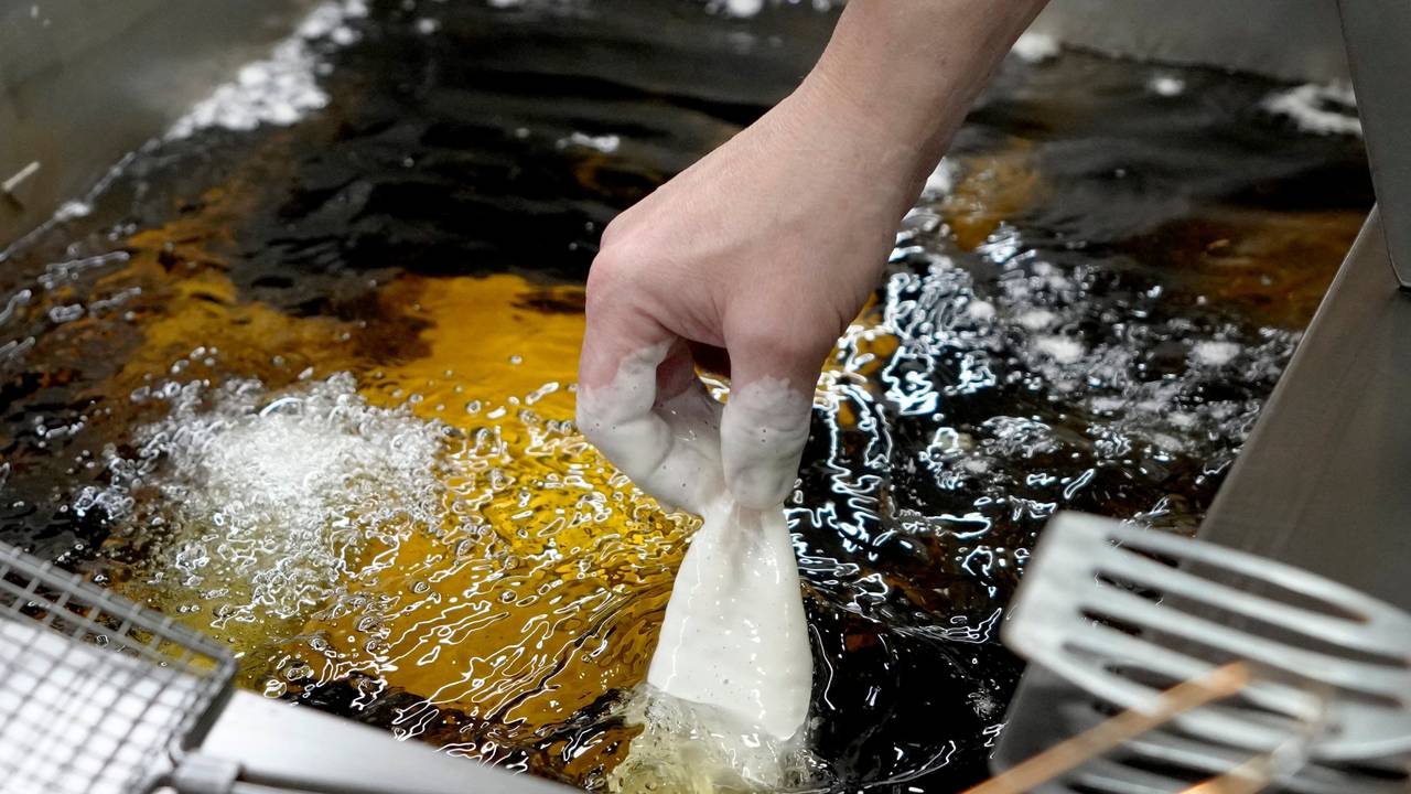 Panierter Fisch wird in heißes Sonnenblumenöl gelegt.