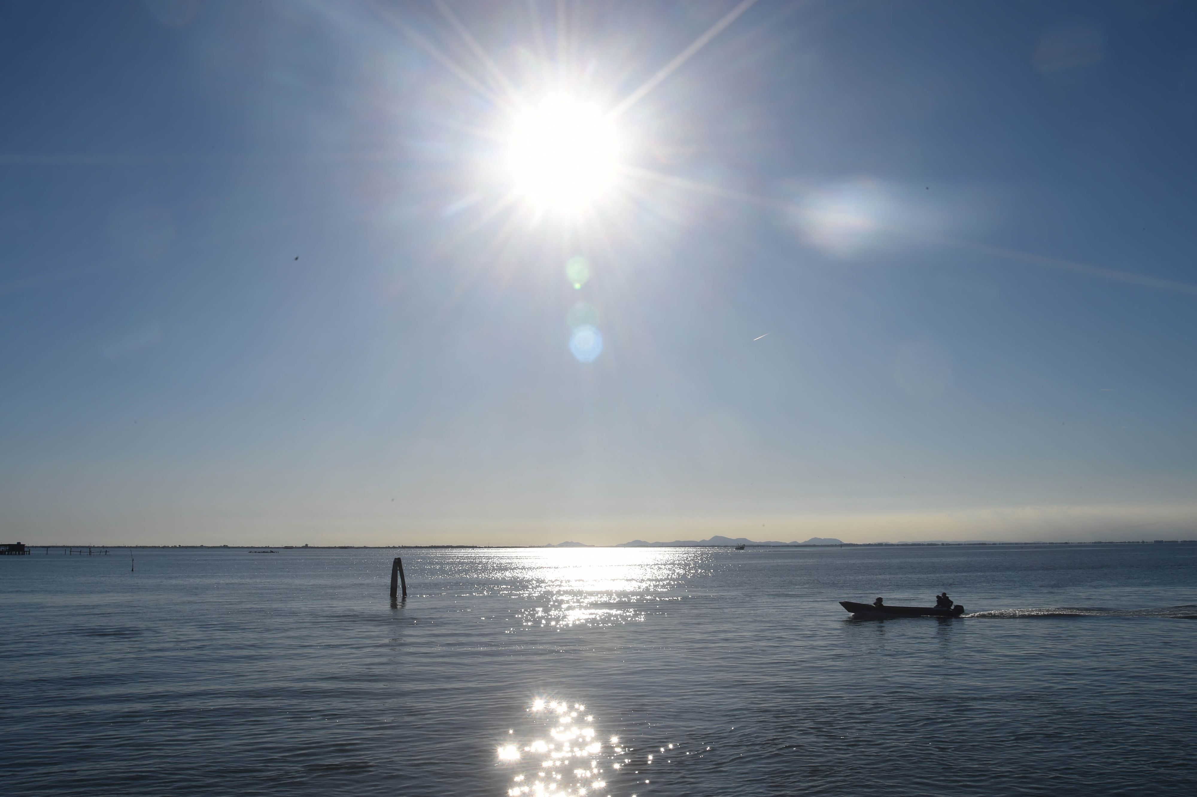 Ein Boot fährt bei Sonnenschein über einen See.