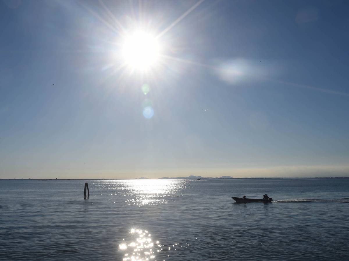 Ein Boot fährt bei Sonnenschein über einen See.