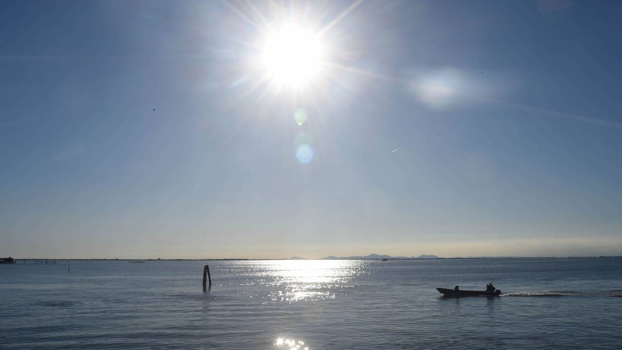 Ein Boot fährt bei Sonnenschein über einen See.