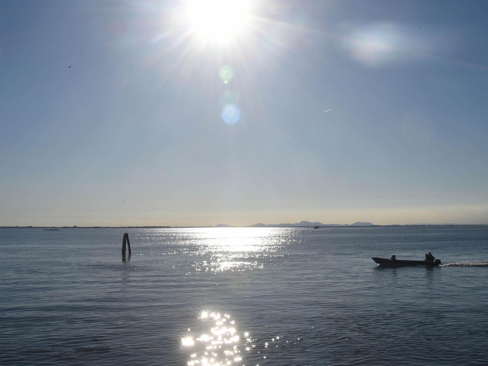 Ein Boot fährt bei Sonnenschein über einen See.