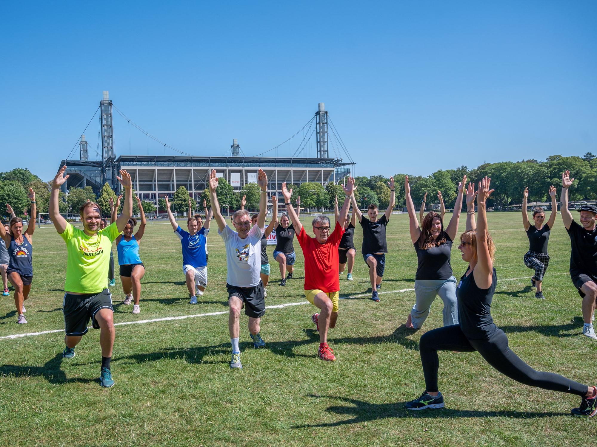 Im Rahmen der Initiative „Kölle aktiv“ macht eine Sportgruppe auf den Jahnwiesen in Köln Fitness-Übungen.
