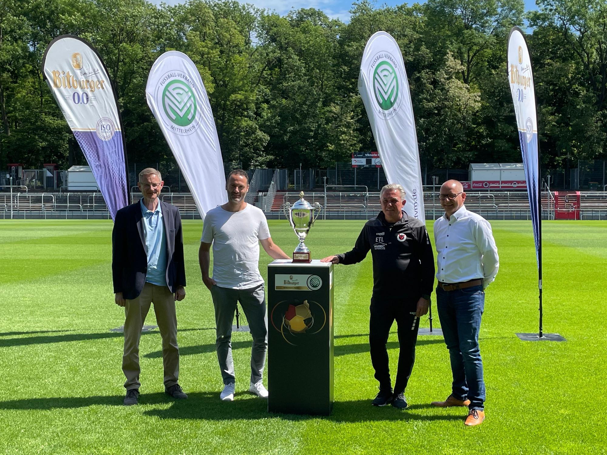 Der Leiter des Sportamts Köln Gregor Timmer, Fortuna Coach Alexander Ende, Viktoria-Trainer Olaf Janßen und Pokalspielleiter Markus Müller von links an. In der Mitte die Trophäe für den Sieger des Mittelrheinpokals.