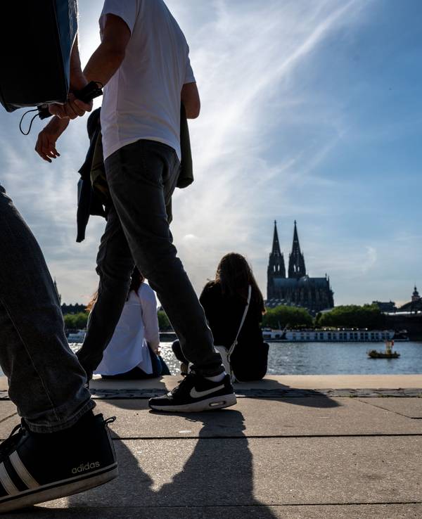 Am Rheinboulevard flanieren junge Leute durch den Sonnenschein.
