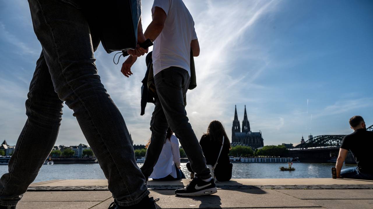 Am Rheinboulevard flanieren junge Leute durch den Sonnenschein.