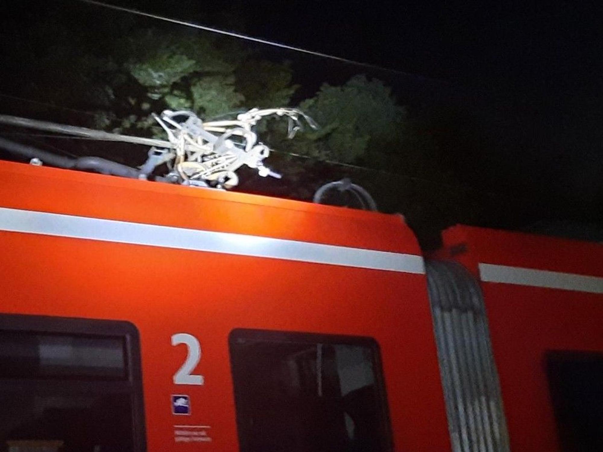 Kaputtes Fahrrad hängt in der Oberleitung eines Zugs.