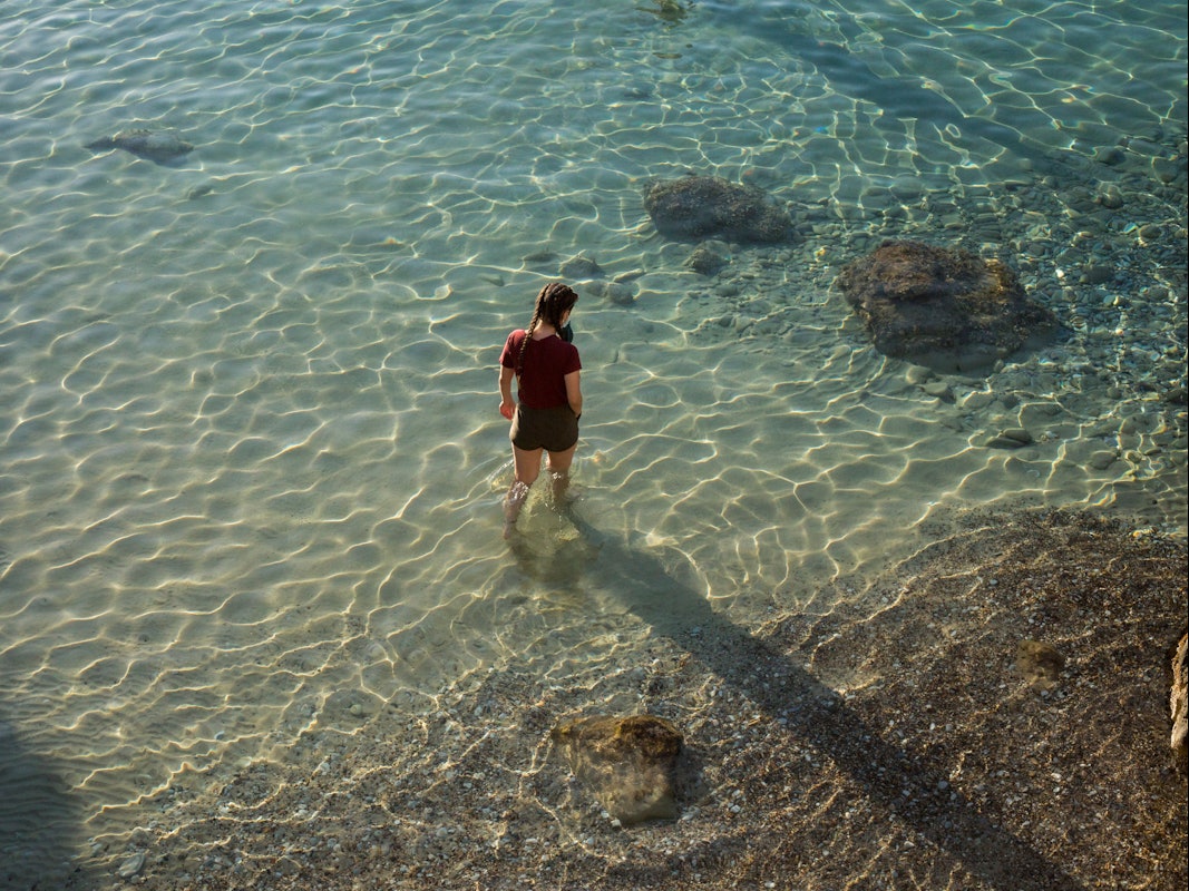 Eine Frau spaziert am 23. Mai 2021 am Strand von Limeni, einem kleinen Fischerhafen auf der Halbinsel Mani in Griechenland.