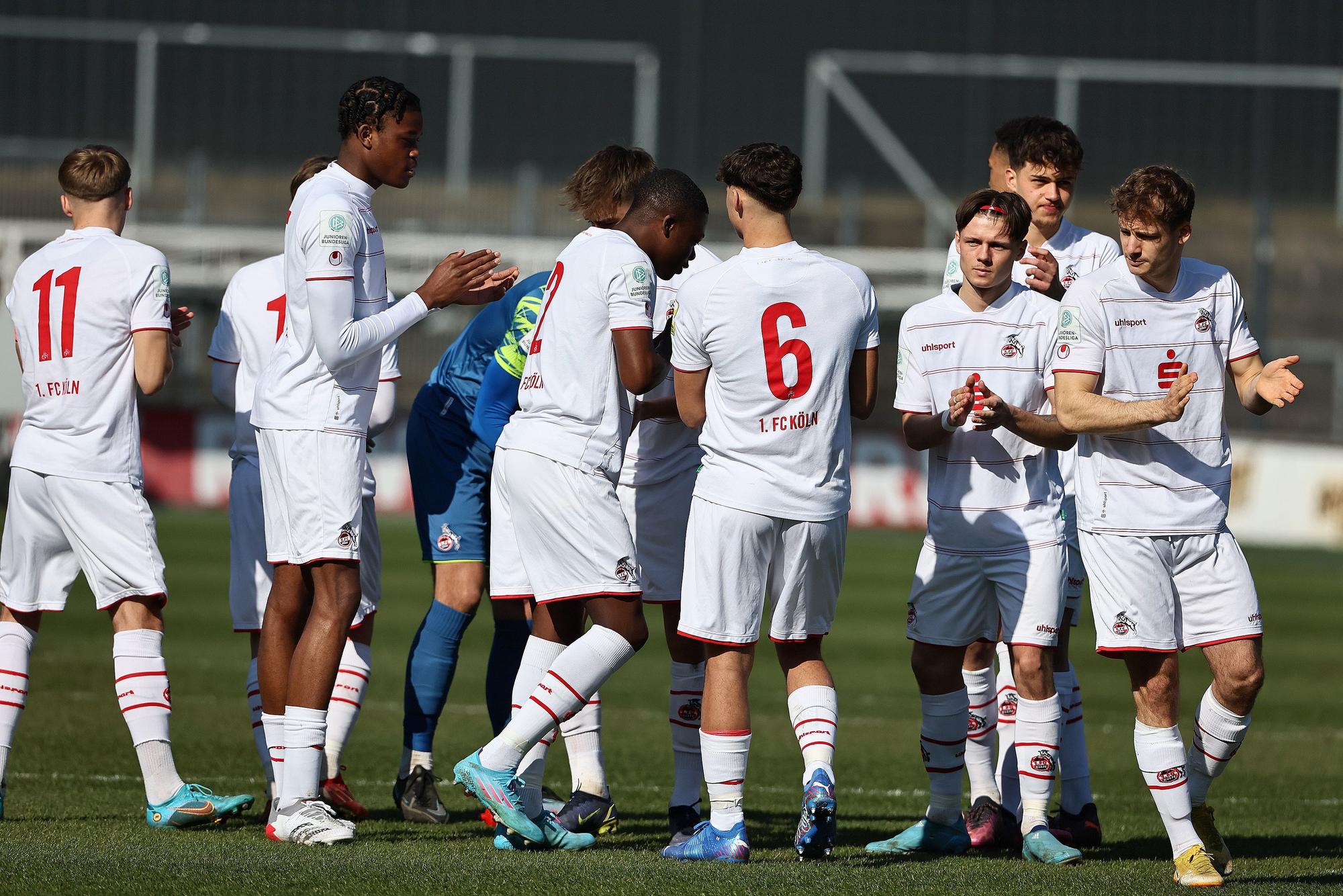 Die Spieler der U19 des 1. FC Köln klatschen sich in einem Spiel ab.