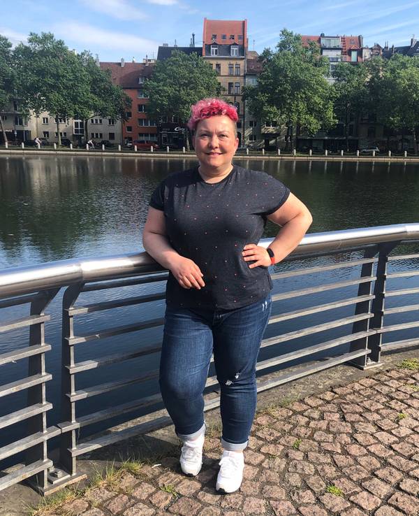 Stadtführerin Jackie Kutz steht an einem Weiher in Köln.