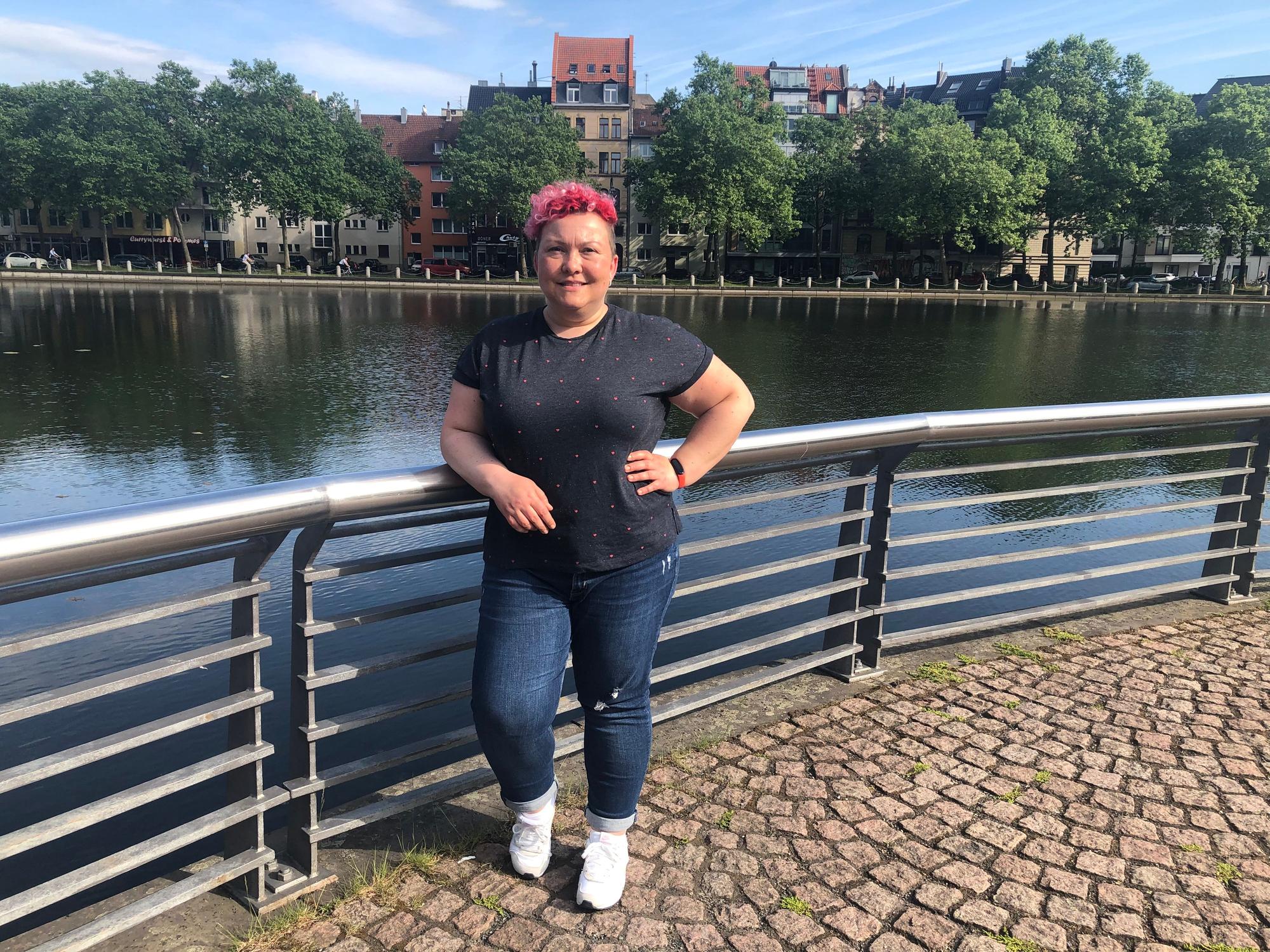 Stadtführerin Jackie Kutz steht an einem Weiher in Köln.