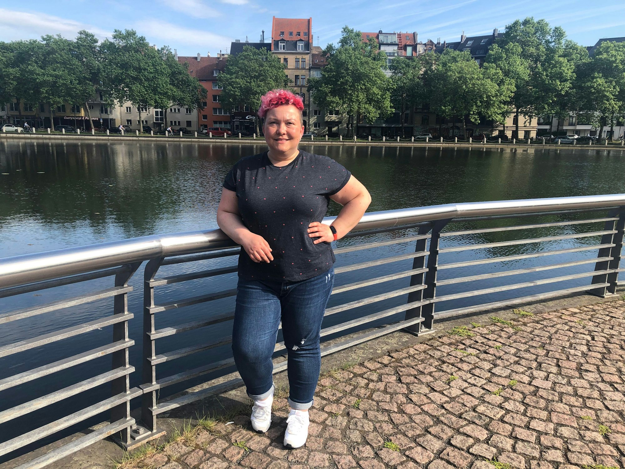 Stadtführerin Jackie Kutz steht an einem Weiher in Köln.