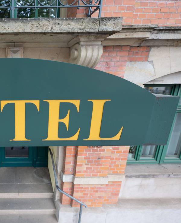 Ein Schild mit der Aufschrift ·Hotel· hängt an einem Hauseingang.