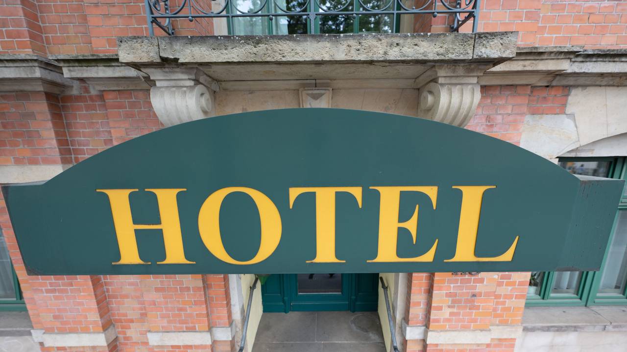 Ein Schild mit der Aufschrift ·Hotel· hängt an einem Hauseingang.