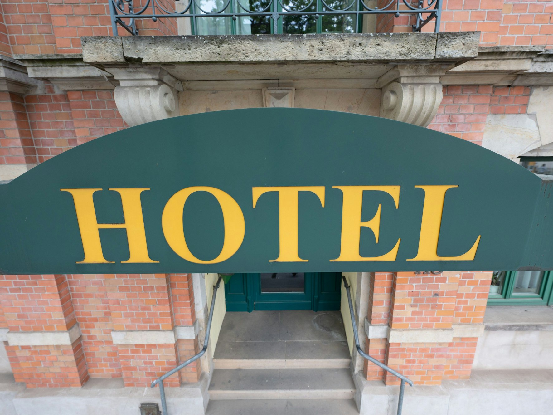 Ein Schild mit der Aufschrift ·Hotel· hängt an einem Hauseingang.