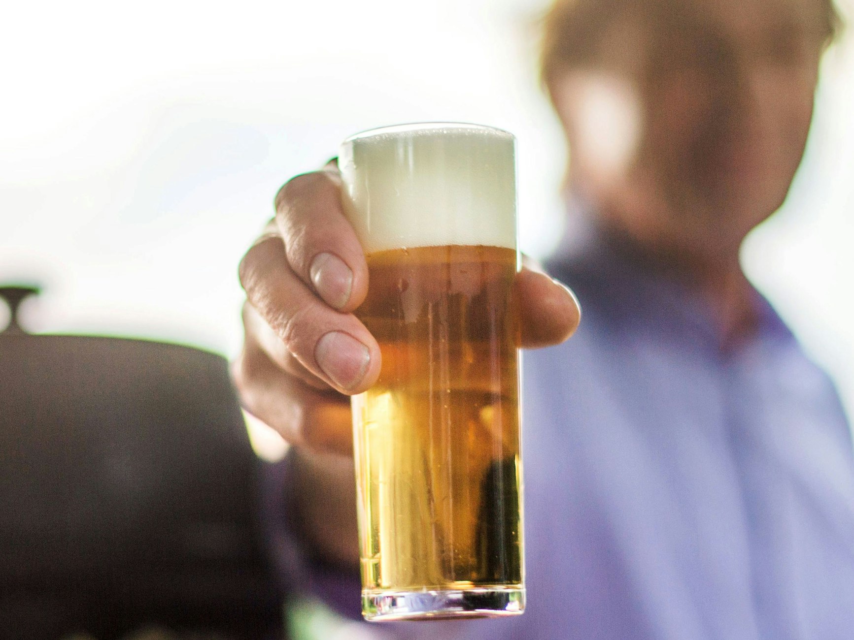 Ein frisch gezapftes Kölsch wird auf einer Party in die Kamera gehalten.