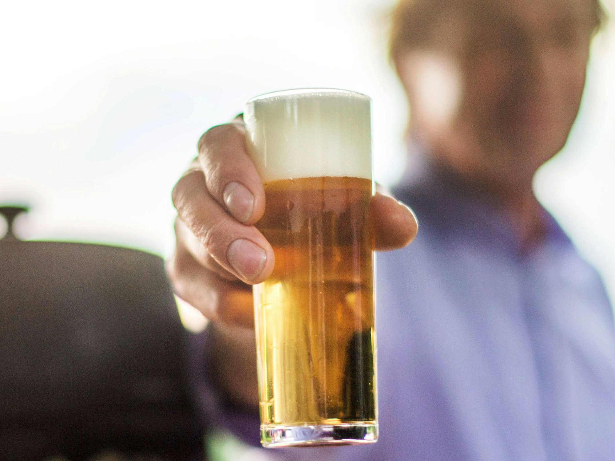 Ein frisch gezapftes Kölsch wird auf einer Party in die Kamera gehalten.