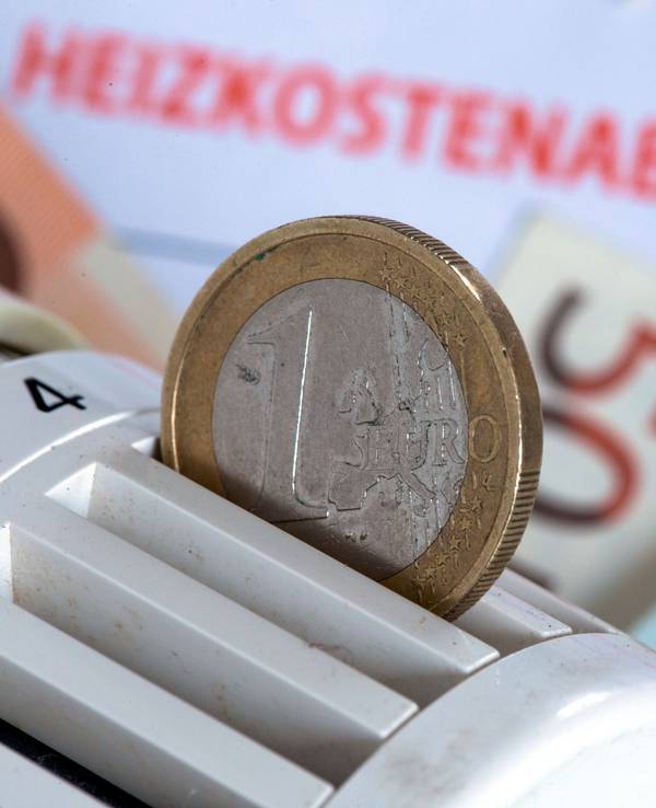 Eine Euromünze steckt am 04. Dezember 2014 in einem Heizungsthermostat, der auf einer Heizkostenabrechnung und Euro-Geldscheinen liegt.