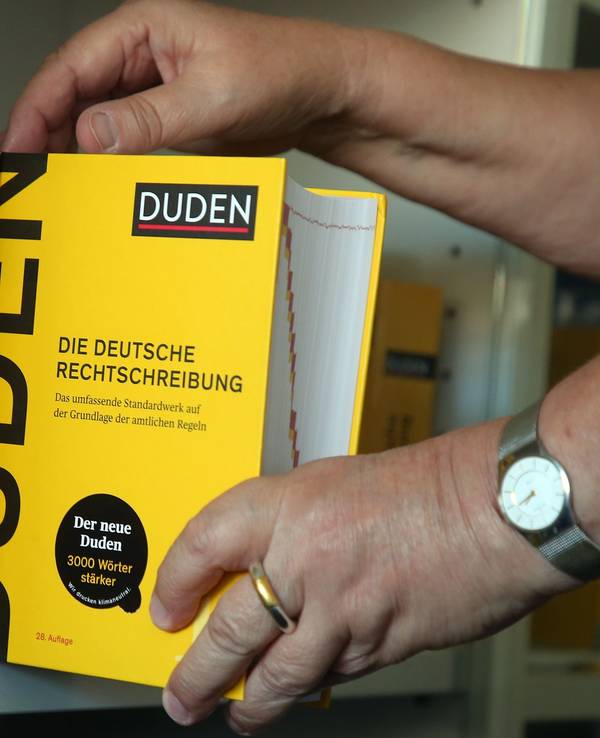 Der Duden wird aus einem Bücherregal gezogen.